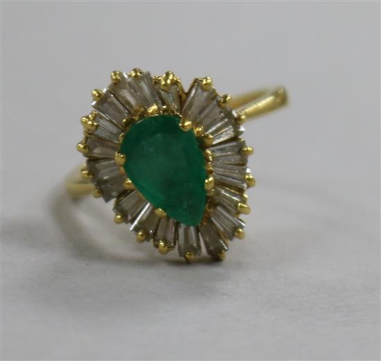 A modern 18ct gold pear shaped emerald and trapeze cut diamond set dress ring, size M.